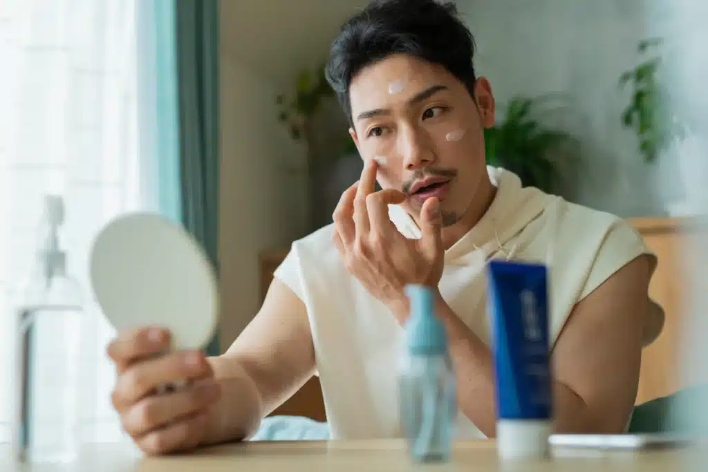 A man applying skincare while looking in the mirror.