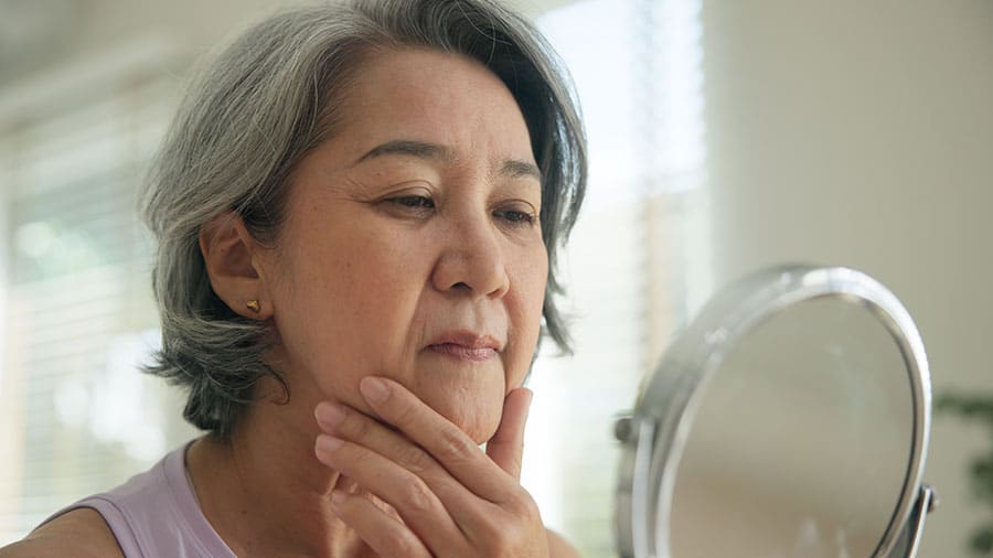 A woman with wrinkles examining her face.